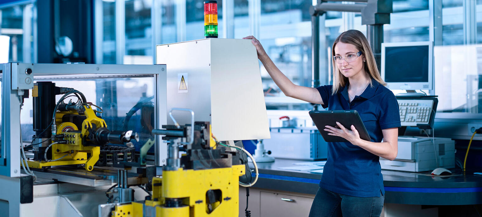 Engineer with tablet PC standing near machine in industry - Arbeitskosten