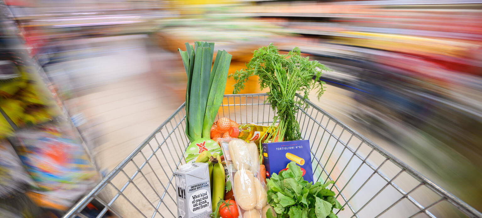  Ein mit Lebensmittel gefüllter Einkaufswagen wird durch einen Supermarkt geschoben - Inflationsmonitor