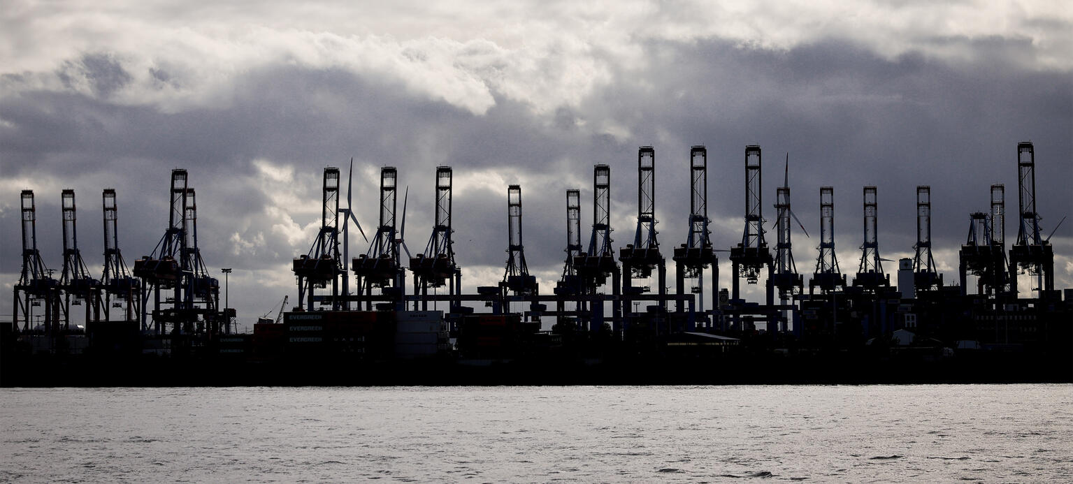 Hochgeklappte Containerbrücken der Terminals Burchardkai und Eurogate sind als Silhouetten im Hafen an der Elbe zu sehen. PM Konjunkturprognose