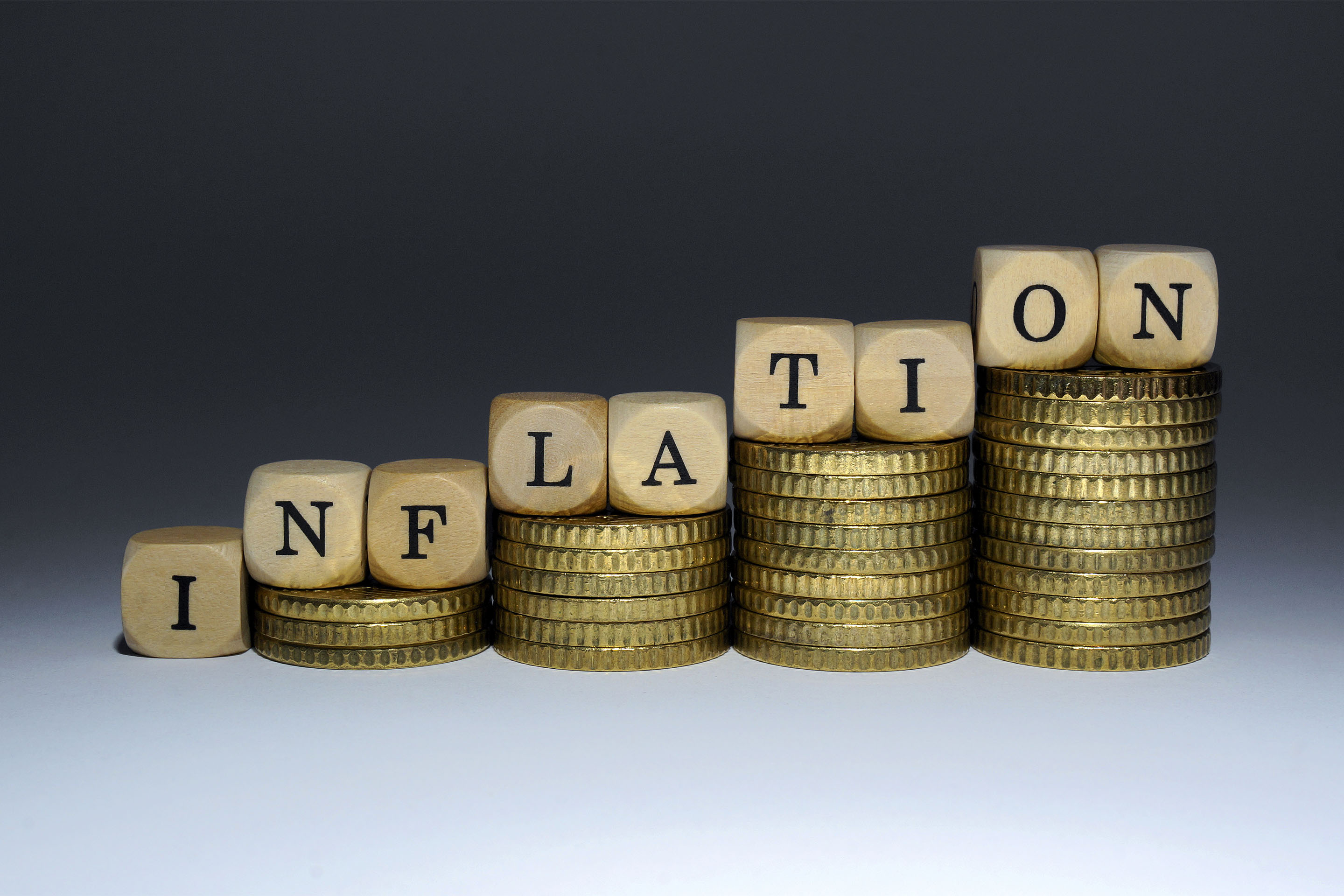 ILLUSTRATION - Buchstabenwürfel auf immer größer werdenden Geldstapeln ergeben das Wort 'Inflation',